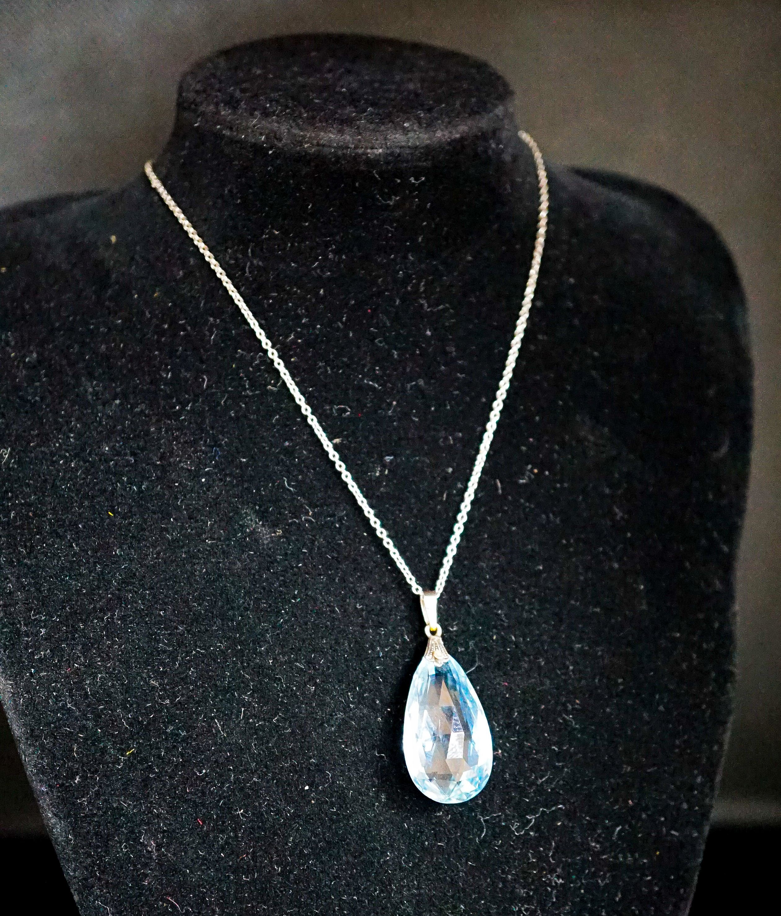 An 18ct mounted facetted pear cut aquamarine set pendant, 33mm, on a 375 white metal fine link chain, 45cm, gross weight 5.2 grams.